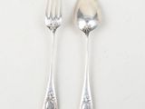 two spoons and a fork on a white table