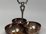 trois bols en métal et une cuillère posés sur une surface blanche
