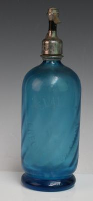 une bouteille en verre bleue avec un bouchon doré, posée sur une surface blanche