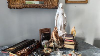 une statue de Jésus assis sur une table, à côté d'une pile de livres