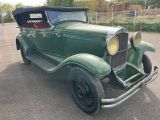an old green car parked in a parking lot