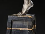 a close up of a statue of a foot on a marble block