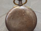 a small silver pocket watch on display in a glass case