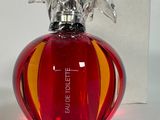 un flacon de parfum rouge avec un bouchon argenté et une boîte en arrière-plan