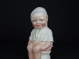 a small figurine of a boy sitting on a toilet