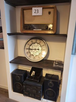 une étagère sur laquelle se trouvent une horloge, des haut-parleurs et une radio