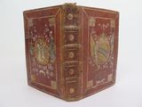 an old red book with gold trim and a decorative design on it