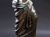 bronze statue of a woman holding a vase in her right hand