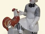 une figurine représentant une femme assise sur un banc avec un coq