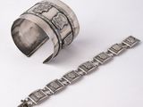 two silver bracelets and a silver bracelet on a white surface
