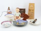 a small doll sitting on a table next to bowls and other items
