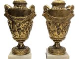 une paire de vases anciens en laiton posés sur des socles en marbre, sur fond blanc