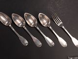 cinq cuillères et une fourchette sur une table noire