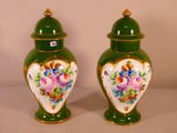 two green vases with flowers on them on a table