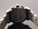 a close up of a watch on a reflective surface with a gray background