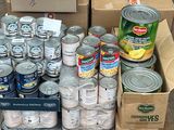 Des cartons de conserves sont empilés sur une palette dans la rue