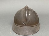 a small metal helmet on a table with a white background