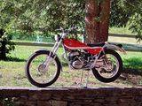 a red motorcycle parked on a stone wall by a tree