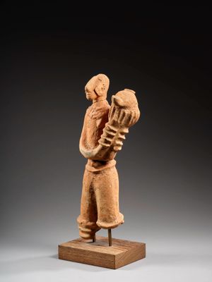 une statue représentant une femme tenant un oiseau, posée sur un socle en bois