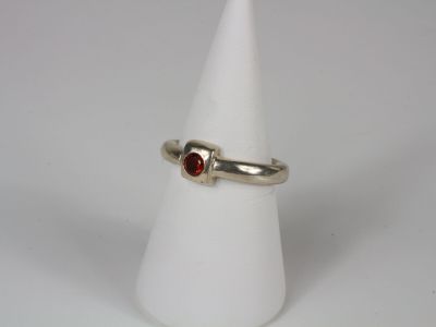a close up of a ring with a red stone on a white cone