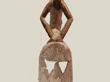 statue of a woman with a hat on her head sitting on top of a rock