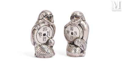 two silver figurines of two birds with chinese writing on them