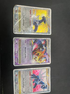 three pokemon cards are on a black surface with a black background