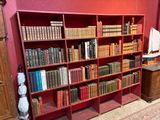 une bibliothèque rouge sur laquelle sont posés de nombreux livres