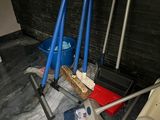several brooms and a toilet in a room with a black brick wall