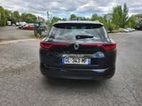 the rear end of a black car parked in a parking lot