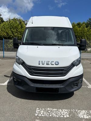 la camionnette blanche est garée sur un parking avec des arbres en arrière-plan
