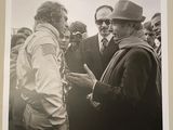 black and white photograph of two men talking to each other in front of a crowd