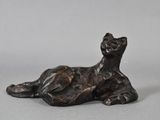 bronze sculpture of a cat laying down on a gray surface
