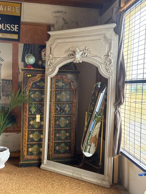 a large mirror in the corner of a room next to a cabinet