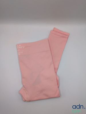 un legging rose posé sur une surface blanche, avec un fond bleu