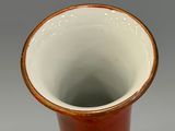 a red and white vase sitting on top of a saucer