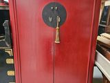 une armoire rouge avec une porte noire et une poignée dorée
