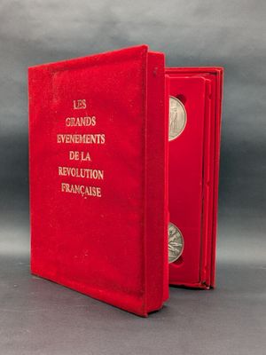 Le livre est ouvert, dévoilant une couverture rouge sur laquelle figure une pièce d'argent.