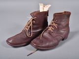 une paire de bottes en cuir marron à lacets, d'où dépasse un os