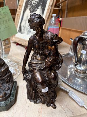 a statue of a woman sitting on a table next to a teapot