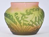a green and pink vase sitting on a white surface