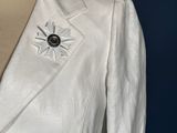 a close up of a white jacket with a brooch on it