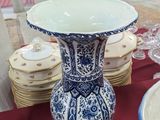 a blue and white vase sitting on a table with plates