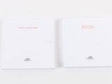 two white notebooks sitting on top of each other on a white surface