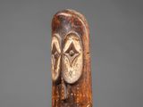 a carved wooden figure of a man with a face on his head