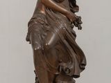 bronze statue of a woman holding a flower on a wooden base