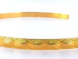 gros plan d'un bracelet en or sur une surface blanche