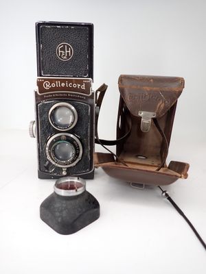an old camera with a leather case next to it