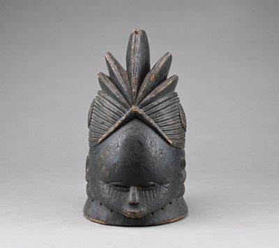 un vieux masque en bois surmonté d'une feuille