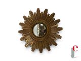 a gold sunburst mirror on the wall next to a white wall